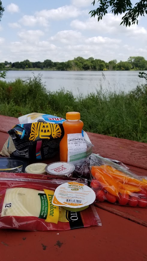 Simple picnic lunch with safe foods for dietary restrictions at a lakeside picnic table