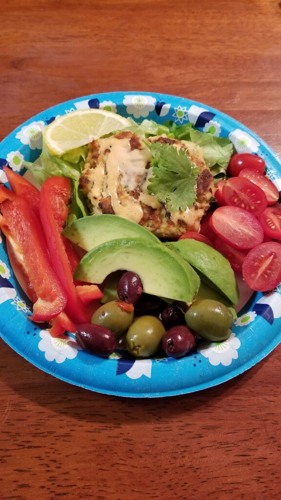Tuna cake served over lettuce with avocado, olives, tomatoes and red bell pepper.