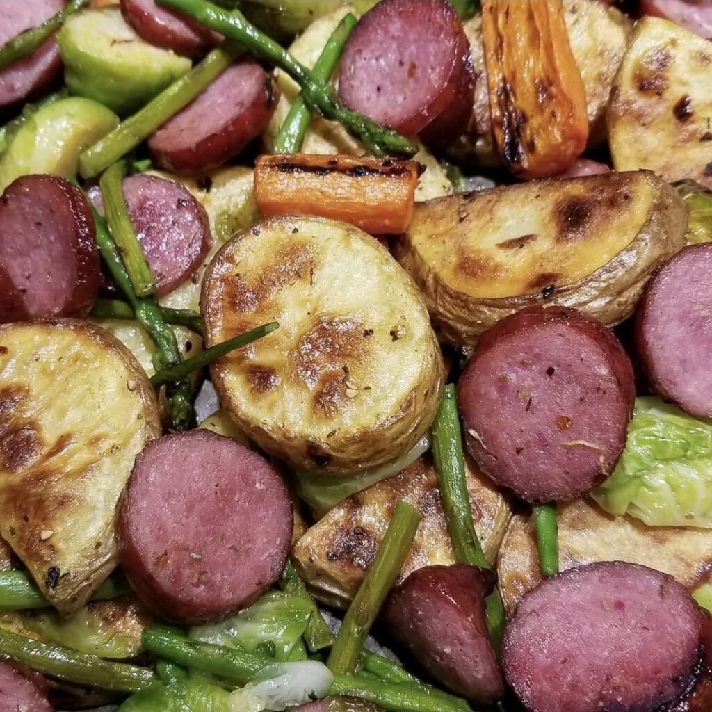 Sheet pan dinner with sliced smoked sausage, roasted potatoes, and mixed vegetables