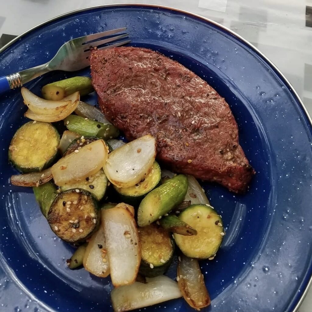 Steak with sauteed zucchini and onions, a simple whole-food meal prepared while traveling with dietary restrictions.